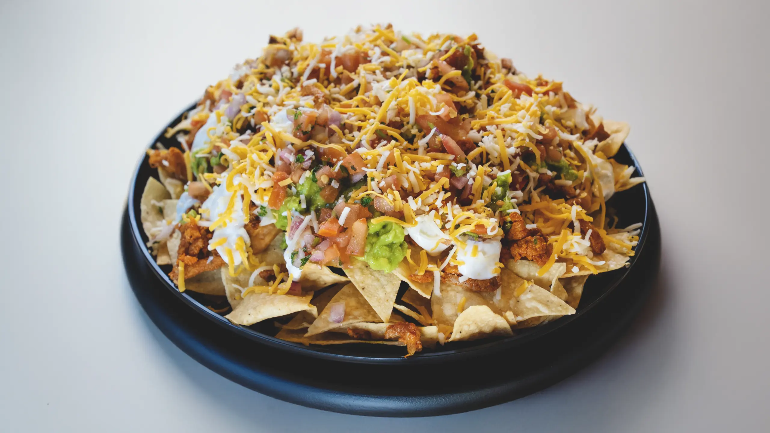 Pastor Nachos with guacamole, sour cream and melted cheese