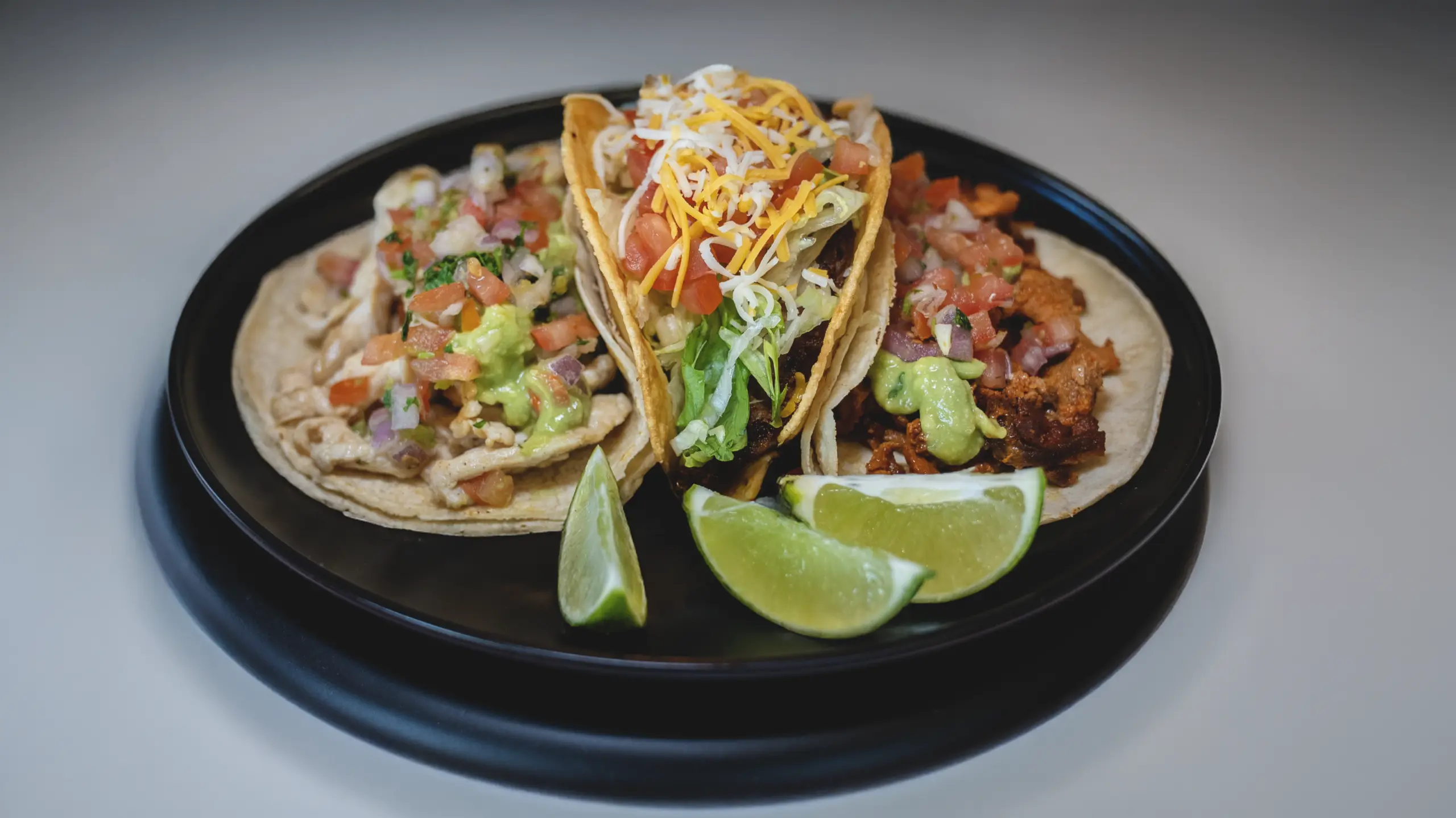 Pastor taco, grilled chicken taco, and shredded beef taco on platter